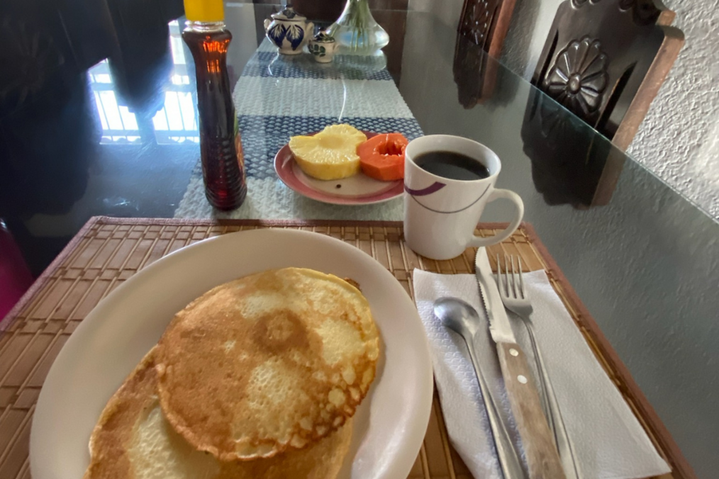 Breakfast consisting of pancakes, coffee, and fruit