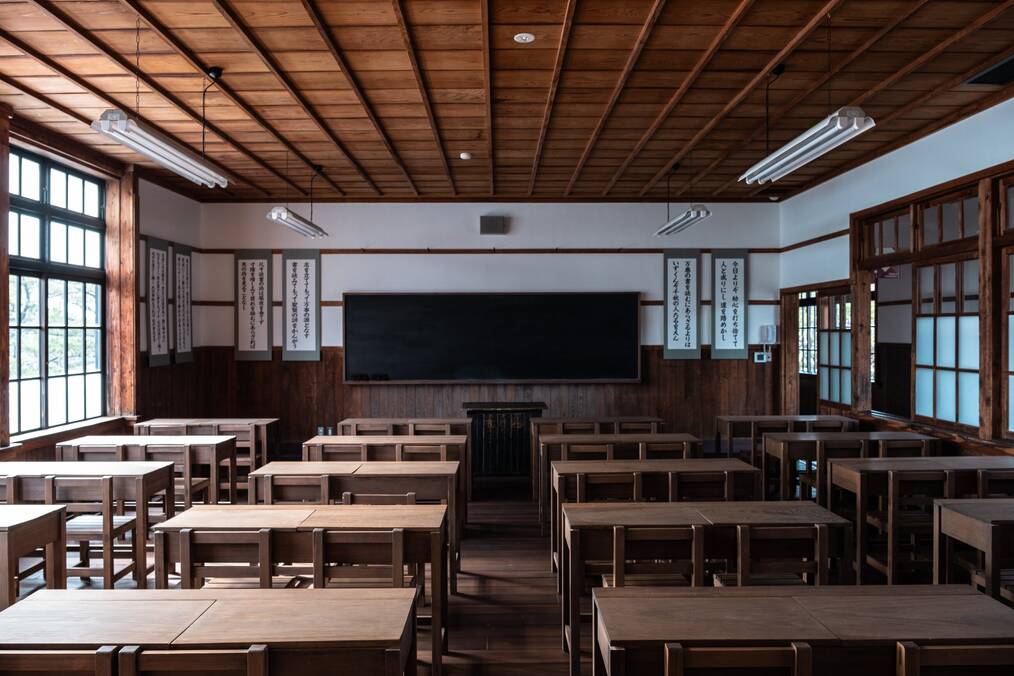An empty classroom of wooden desks in Japan.