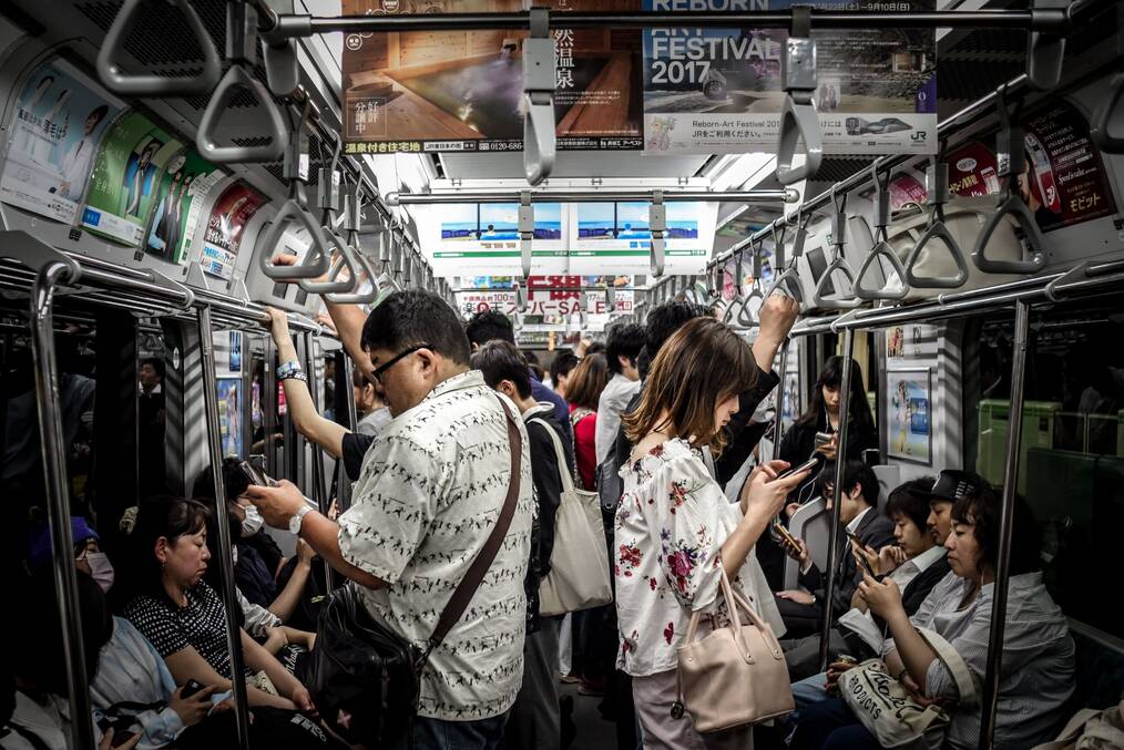 People stand in a crowded metro car in Japan.