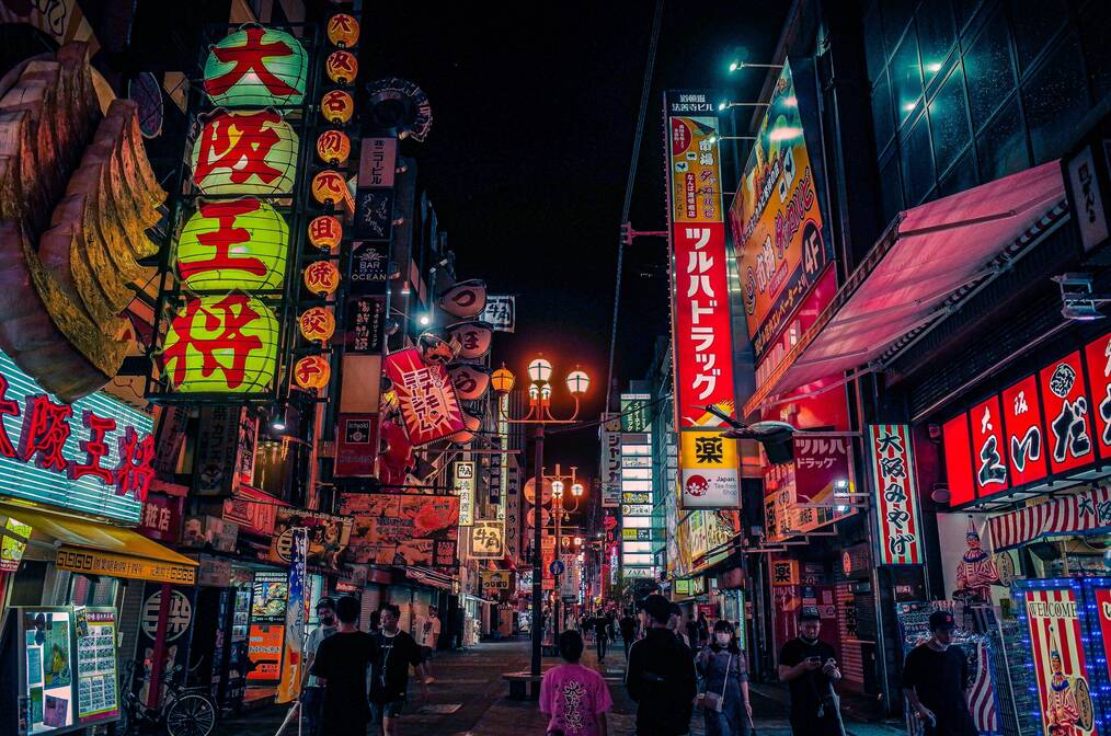 Brightly lit neon signs at night on a Japanese street.