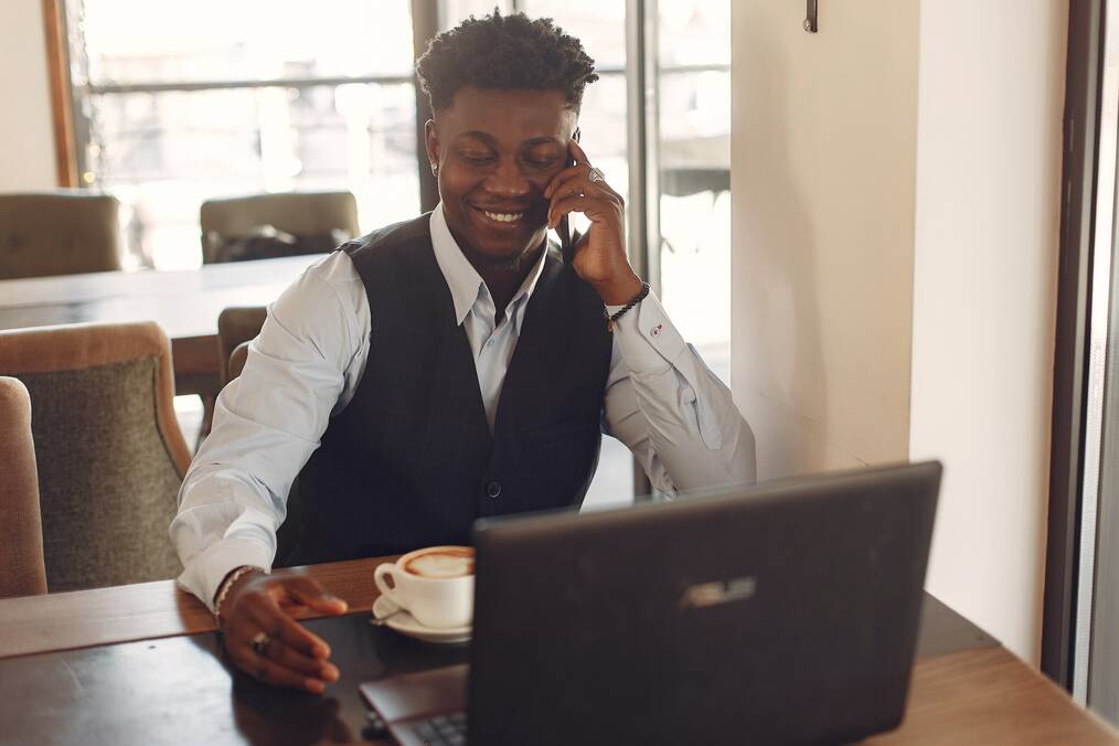 Person Sitting by the Table Working While Having Coffee