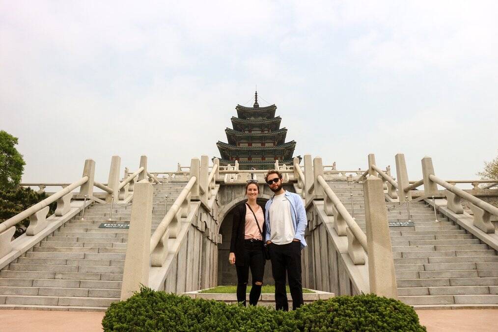 A man and woman stand in front of a temple.