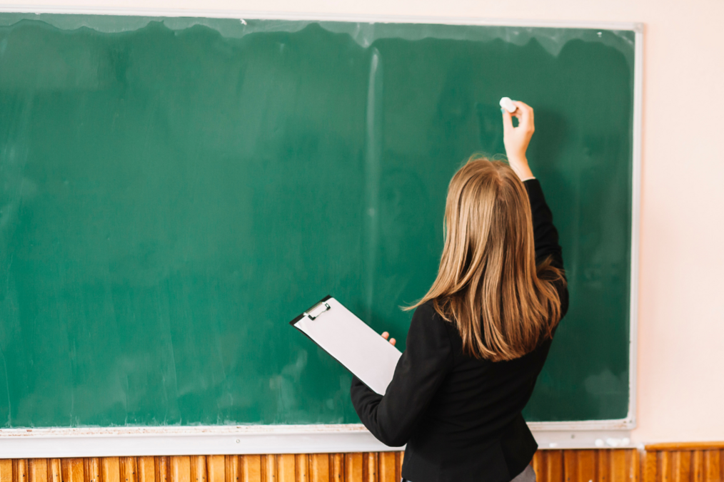Teacher writing on chalk board
