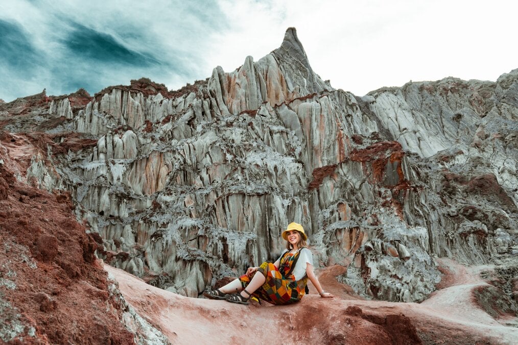 Traveler sitting and smiling in front of cliff wall