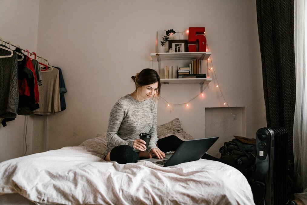 Student sitting on bed while using laptop
