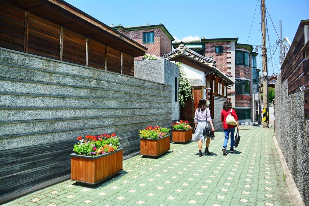 Two women walk down a back alley in Korea.