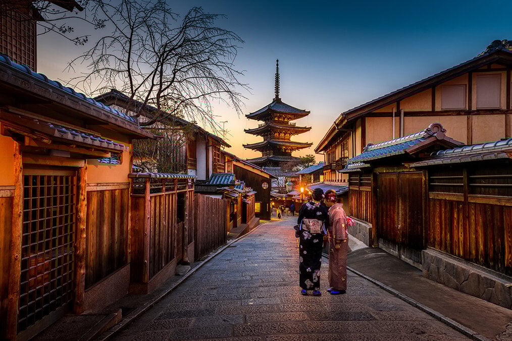 Photo via Unsplash Two women in Japan walking down an alley at sunset