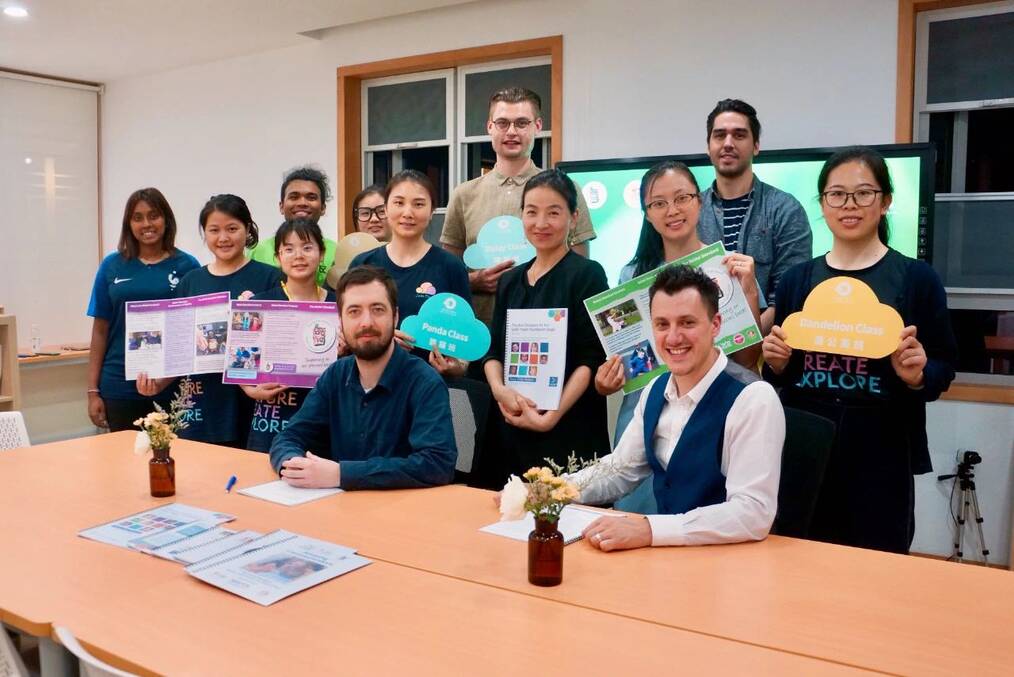 A group of TEFL teachers smile and pose around a table.