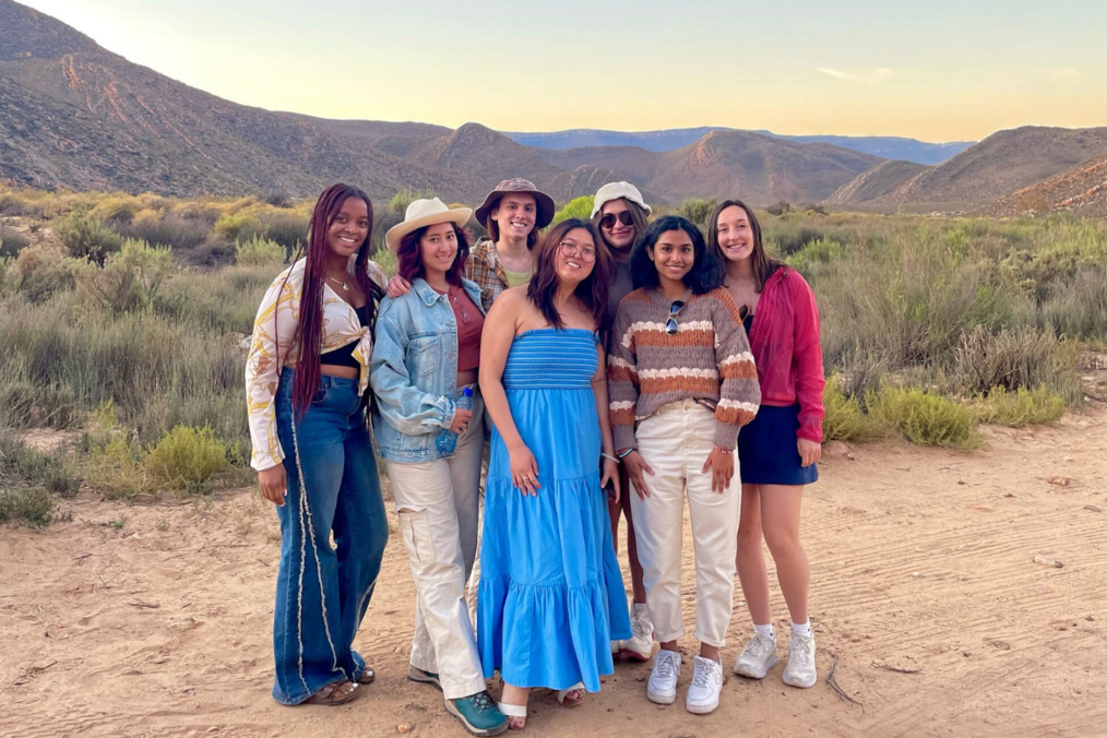 Group of travelers smiling during sunset in the desert