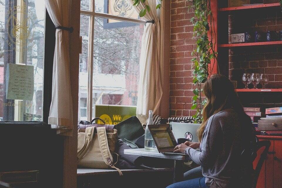 A woman works on a laptop in a cafe.