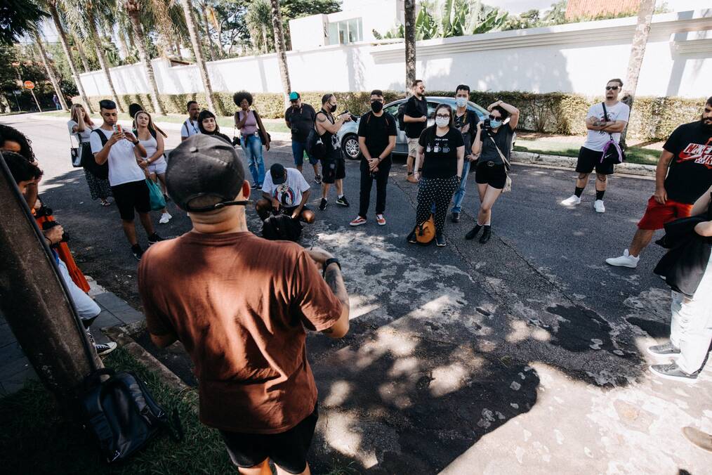 A tour guide talks to a group of people on the street.