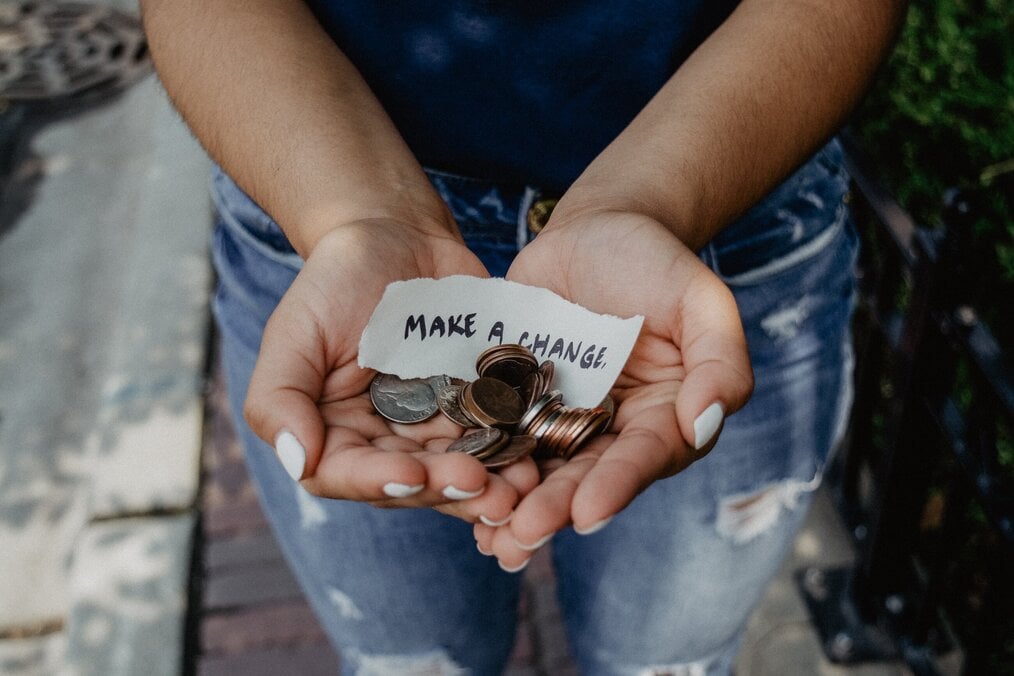 Photo by Katt Yukawa on Unsplash Hands hold coins and a note that says, "make a change".