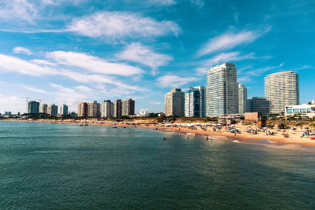 Photo by Pedro Slinger on Unsplash High rise buildings line a white sand beach.