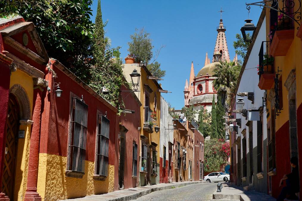 Red and yellow buildings line a street in Mexico.