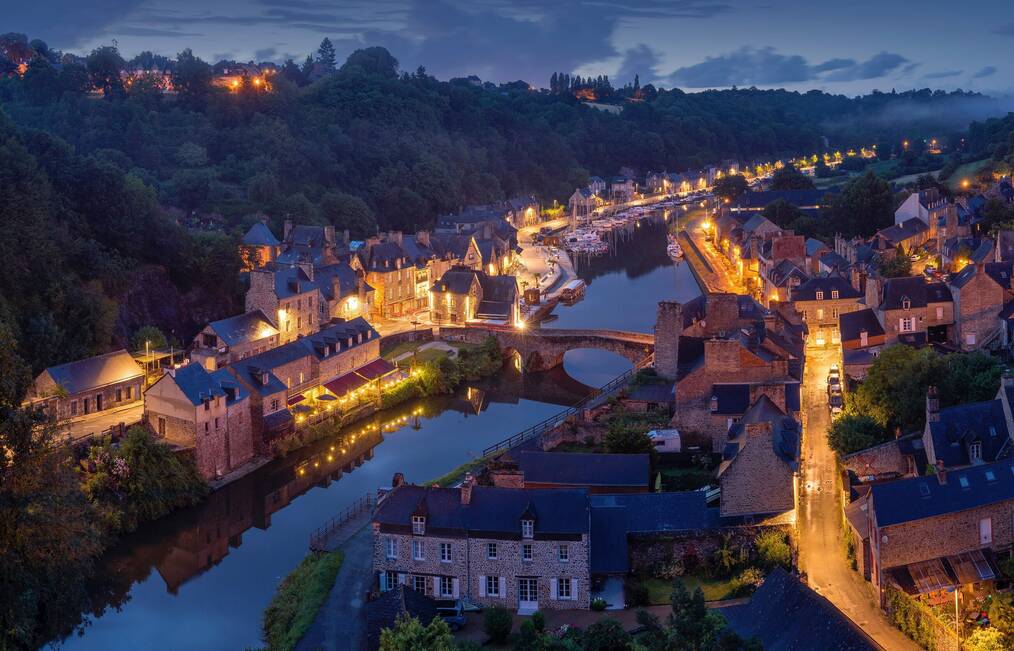 A night scene of a French village along a river.
