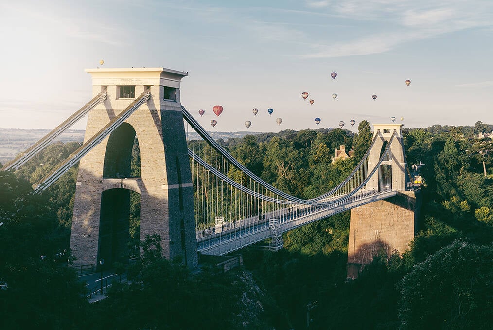A photo of a bridge in Bristol with hot air balloon's in the background
