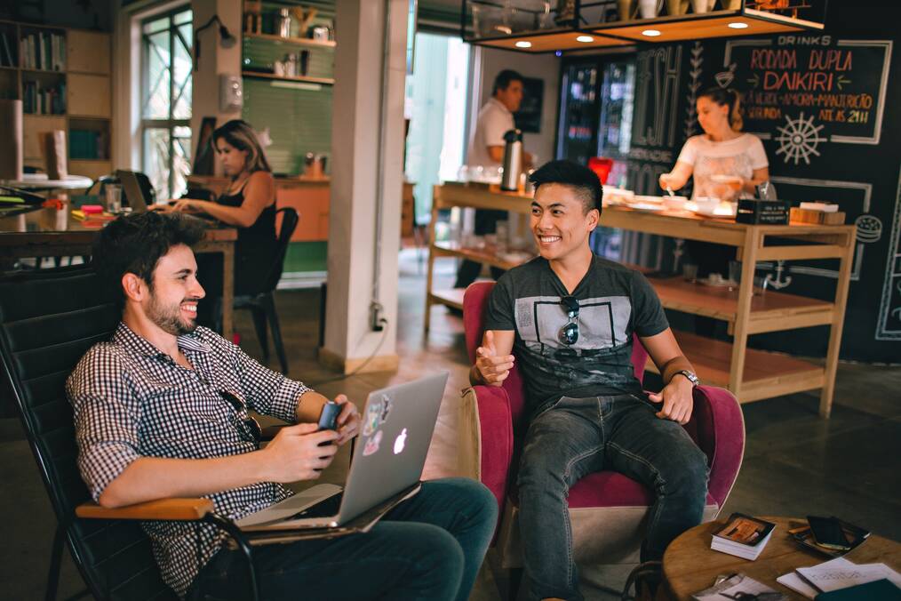 Two men sit in chairs laughing and talking.