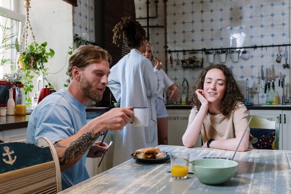 People sit at a kitchen table talking.