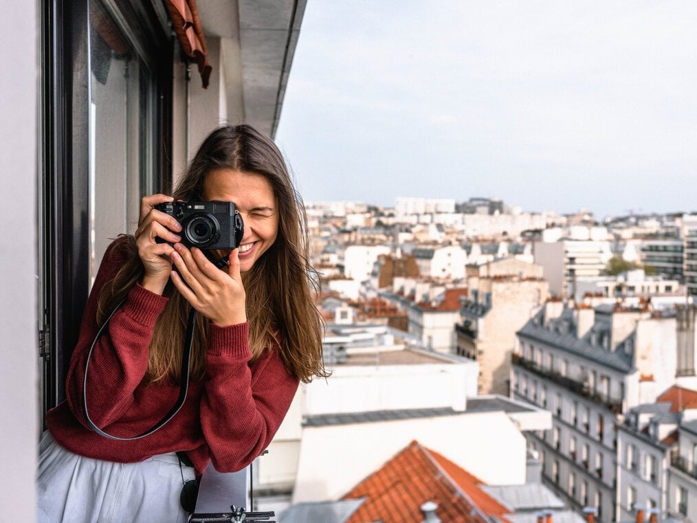 Woman taking a photo while standing on a balcony