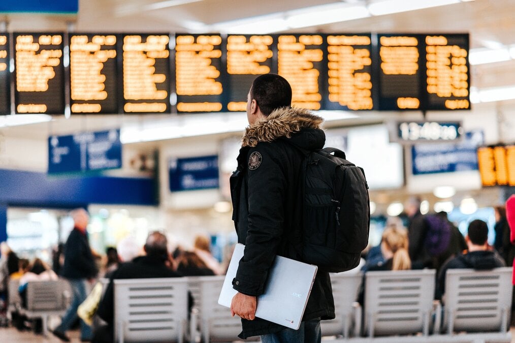 A man looks at a flight board in an airport.