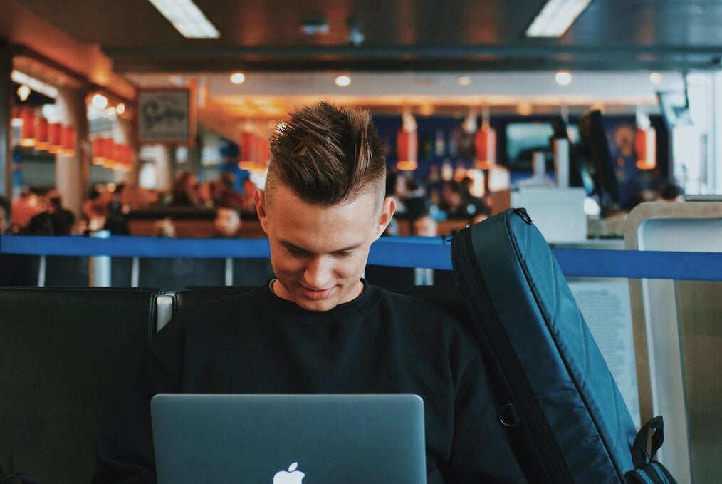 A man works on a laptop in an airport.