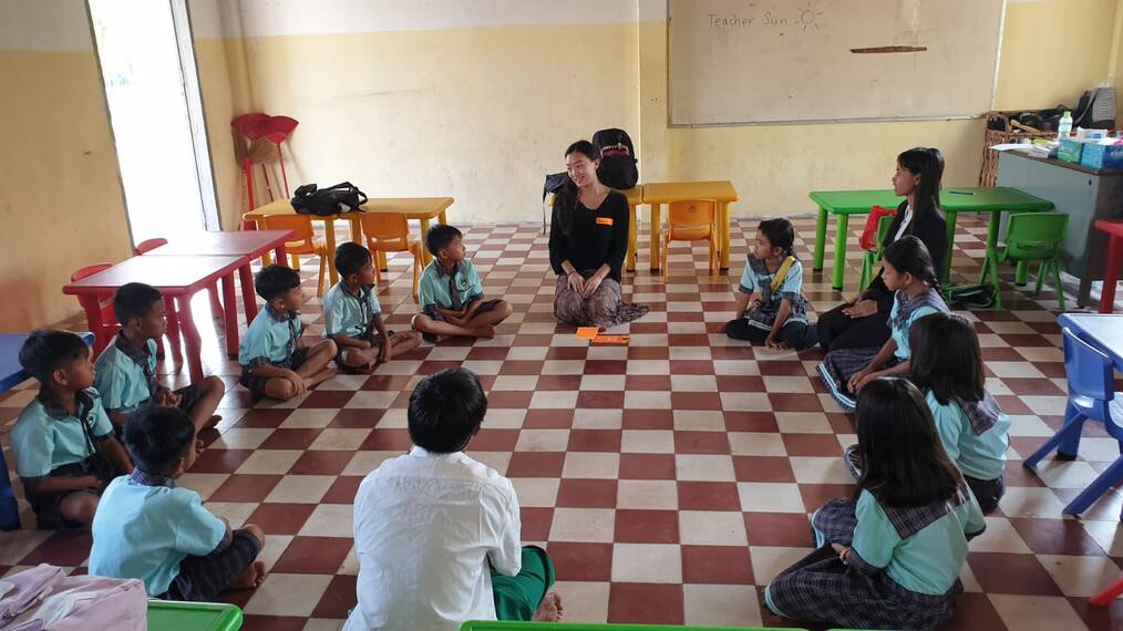 Volunteer sitting in a circle on the floor with students in the classroom