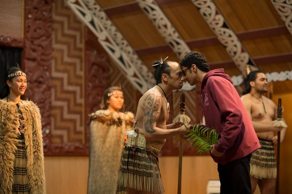 Student in red hoodie doing a traditional Māori greeting with tribe member