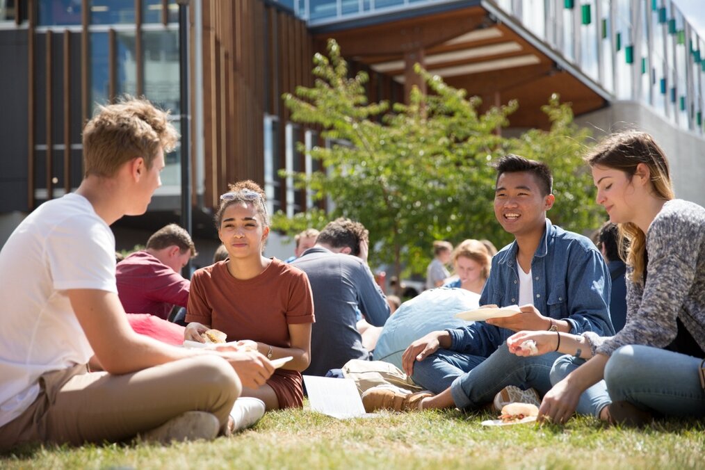 Credit: Education New Zealand Group of students sitting on grass and eating together