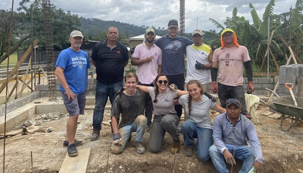 Max Niv Volunteers stand at building site.