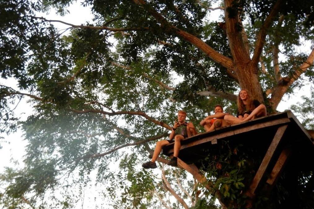 Three students sitting in a treehouse