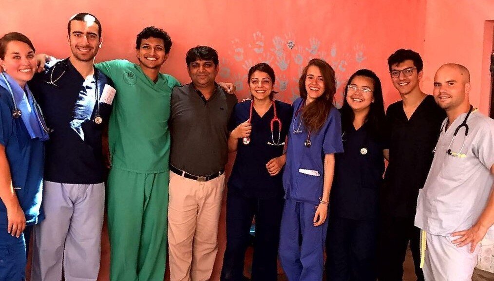 IVHQ A group of healthcare volunteers wearing scrubs stand and smile.