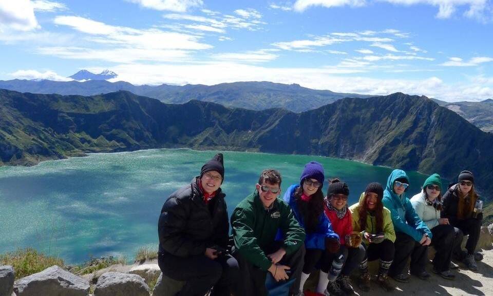 A group poses in front of a lake and mountains.
