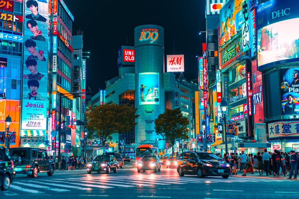 Neon lights shining on a busy street in Japan.