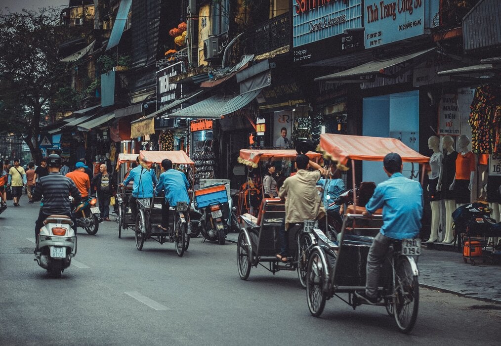 Photo by Tran Phu on Unsplash Pedicabs ride down a street in Vietnam.