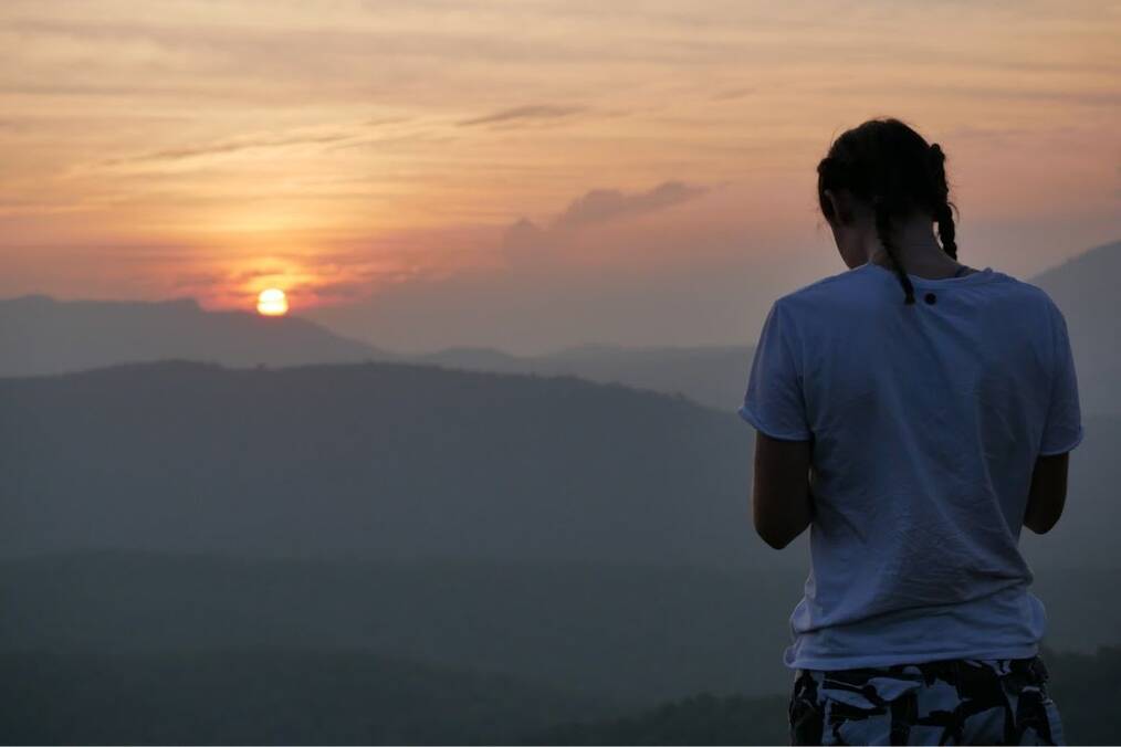 Traveler looking towards sunset over horizon