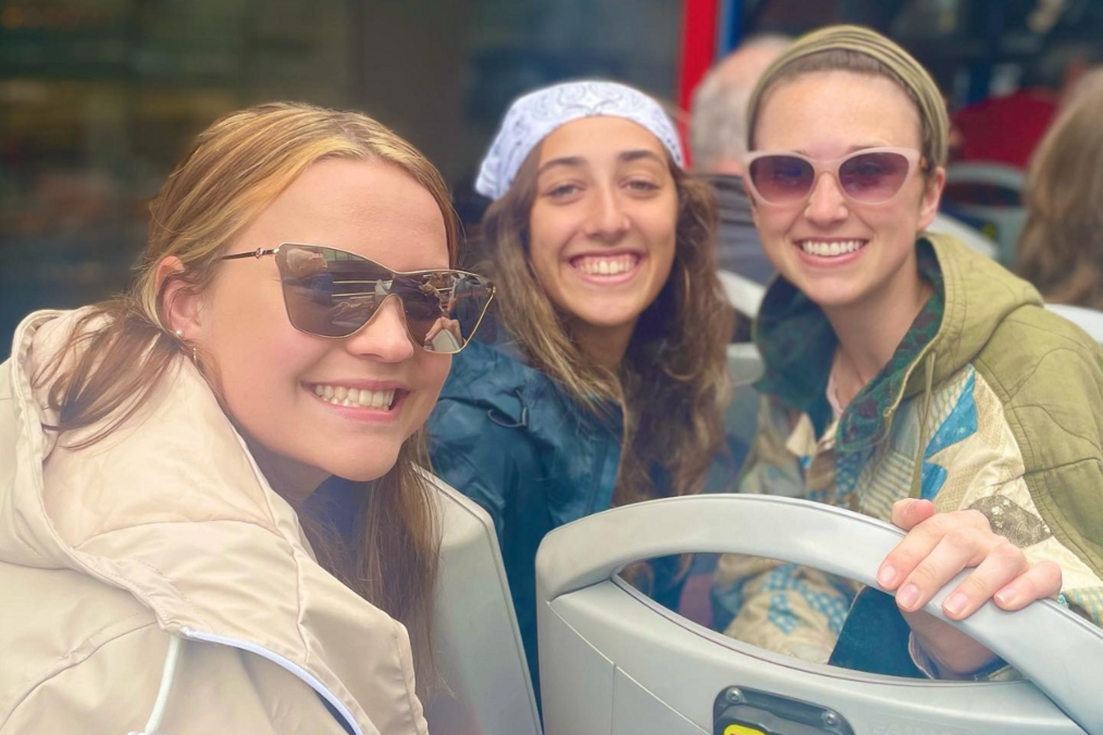 Three people smiling while sitting in a bus