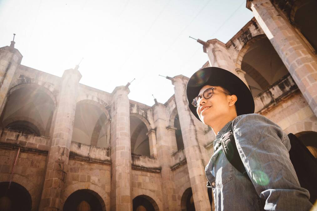A man stands in the sun by a building.