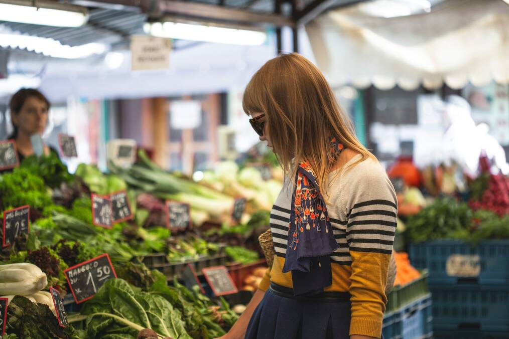 A woman looks at produce at an outdoor market.