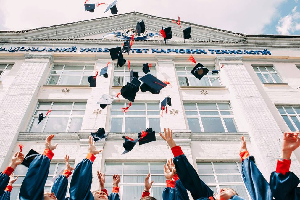 Students throw caps in the air at graduation.