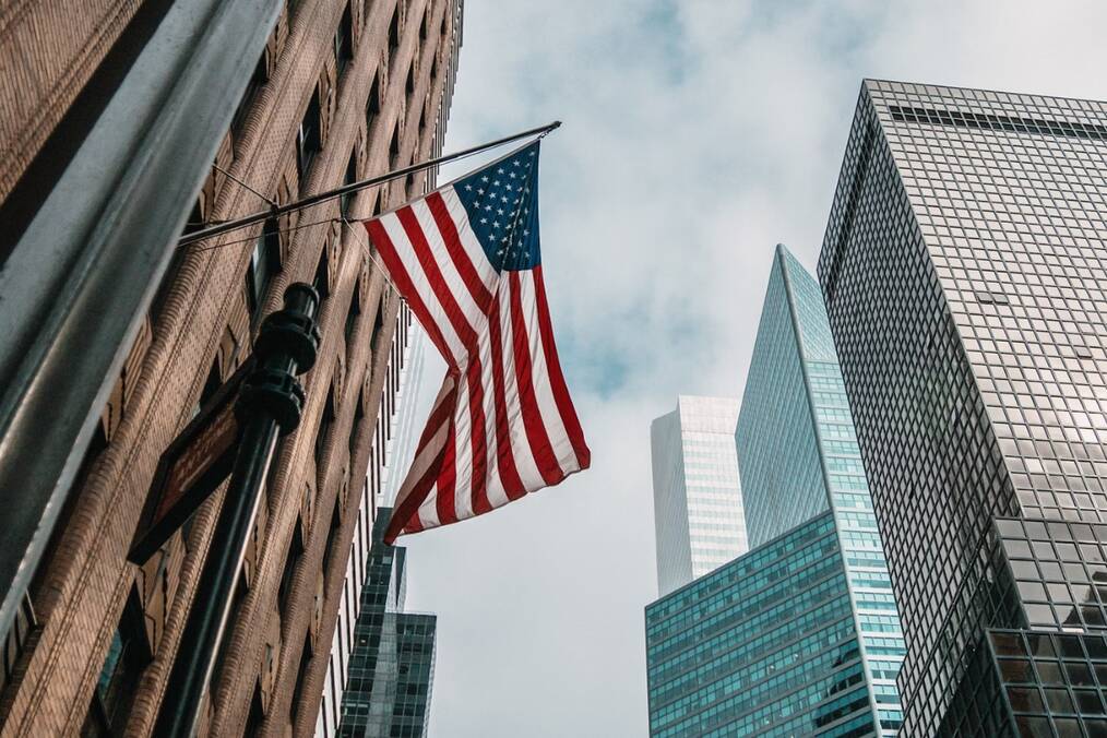 An American flag beneath skyscrapers