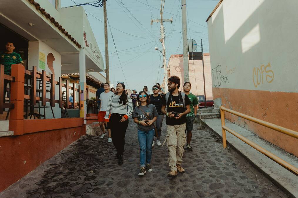 A group of people walk down a street in Mexico.