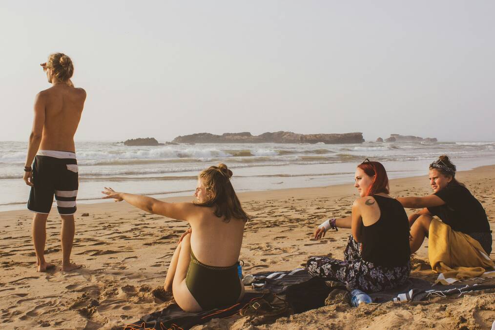 Three women sit on a beach.