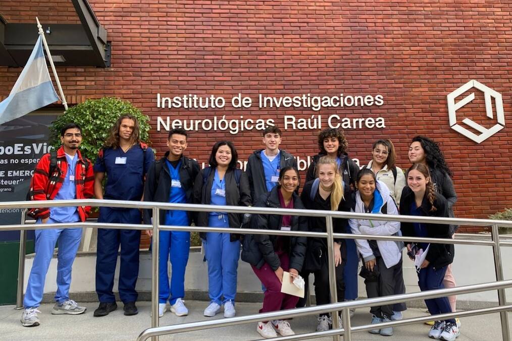 A group of science students abroad posing in front of their department