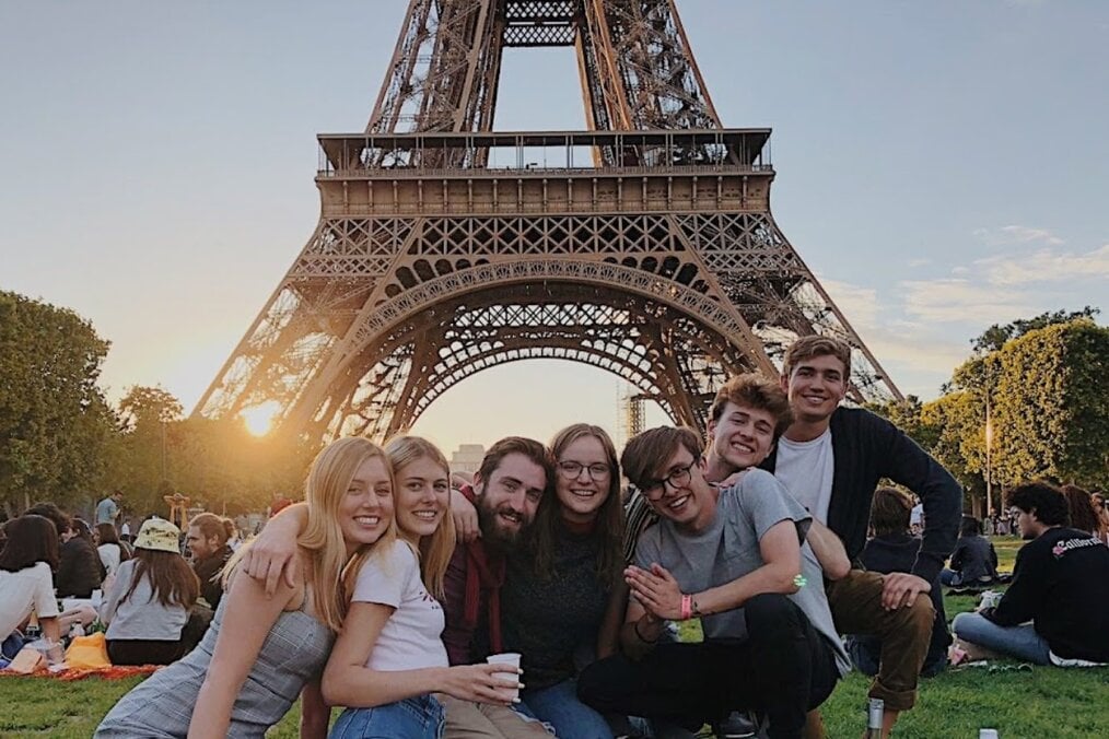 Study Abroad France Friends sitting underneath the Eiffel Tower in Paris, France