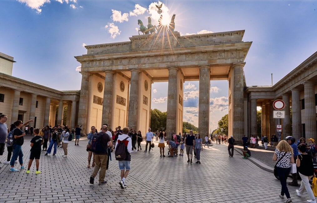 Photo by Norbert Braun on Unsplash People walk near the Brandenburg Gate in Berlin.