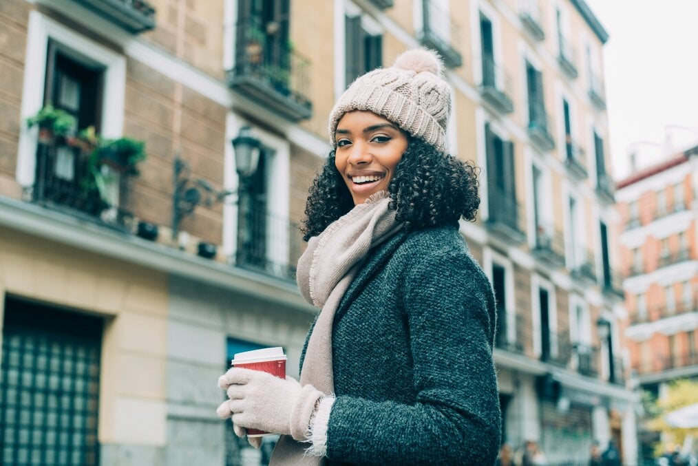 Unsplash Getty woman Madrid A woman in a coat and hat poses in front of buildings in Madrid.