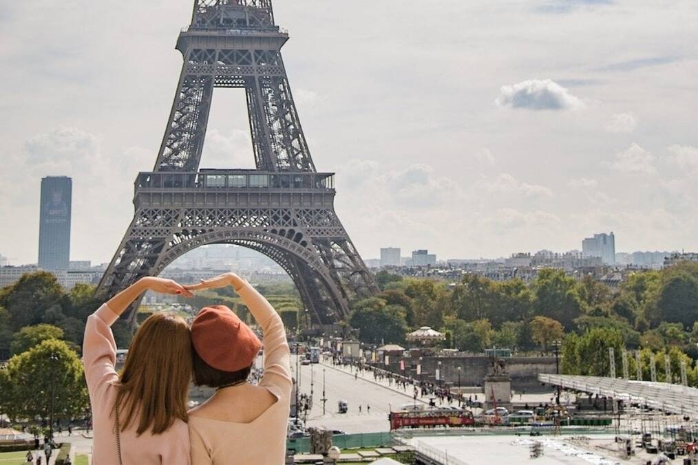 Two people creating a heart sign by the Eiffel Tower 