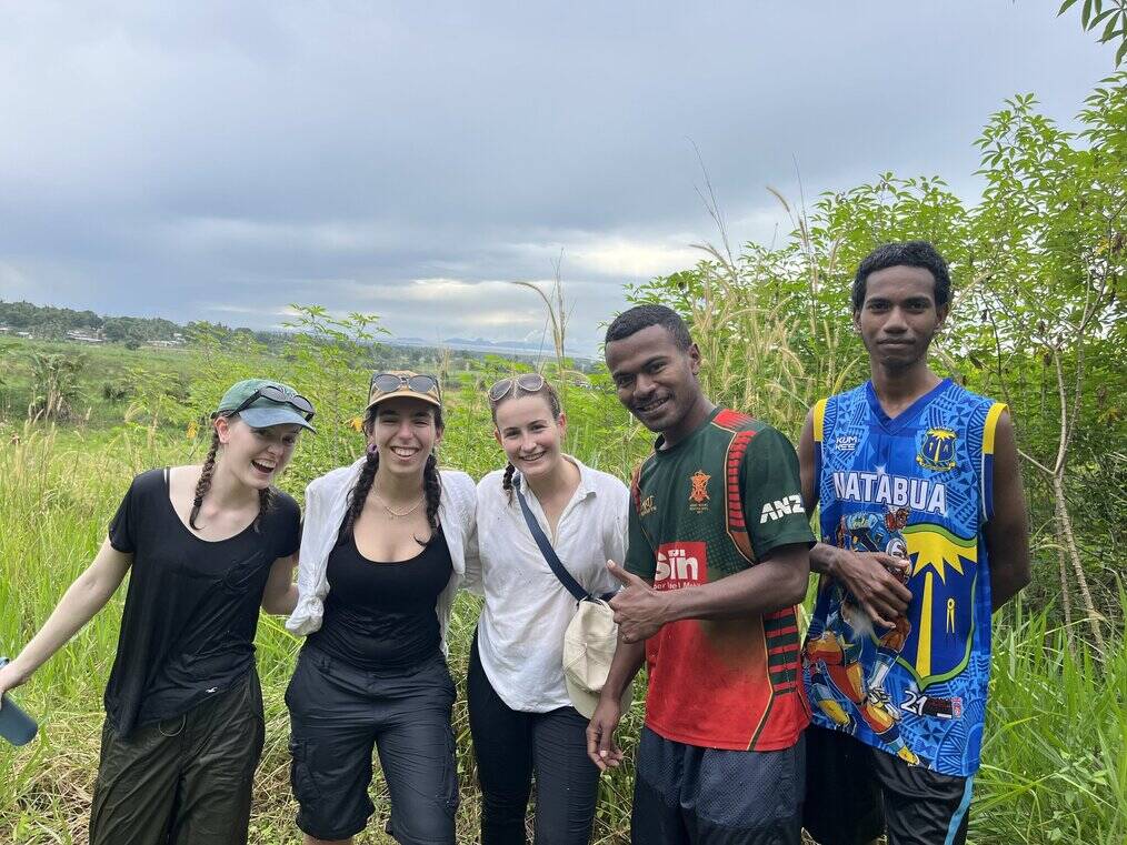 A group of men and women in Fiji stand together and smile.