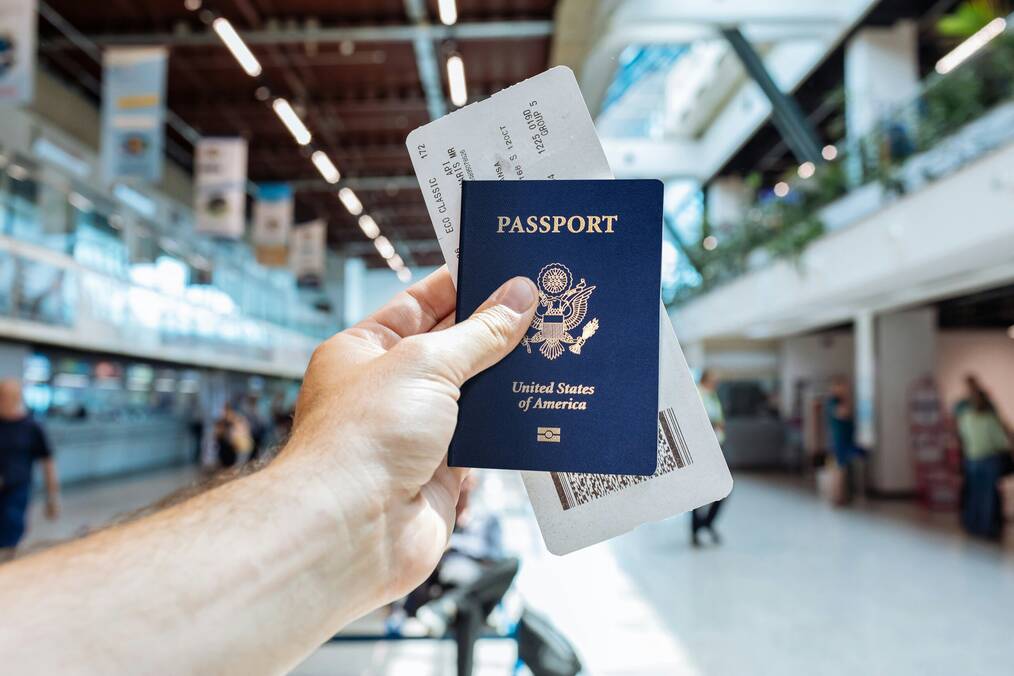 A hand holding a US passport in an airport.