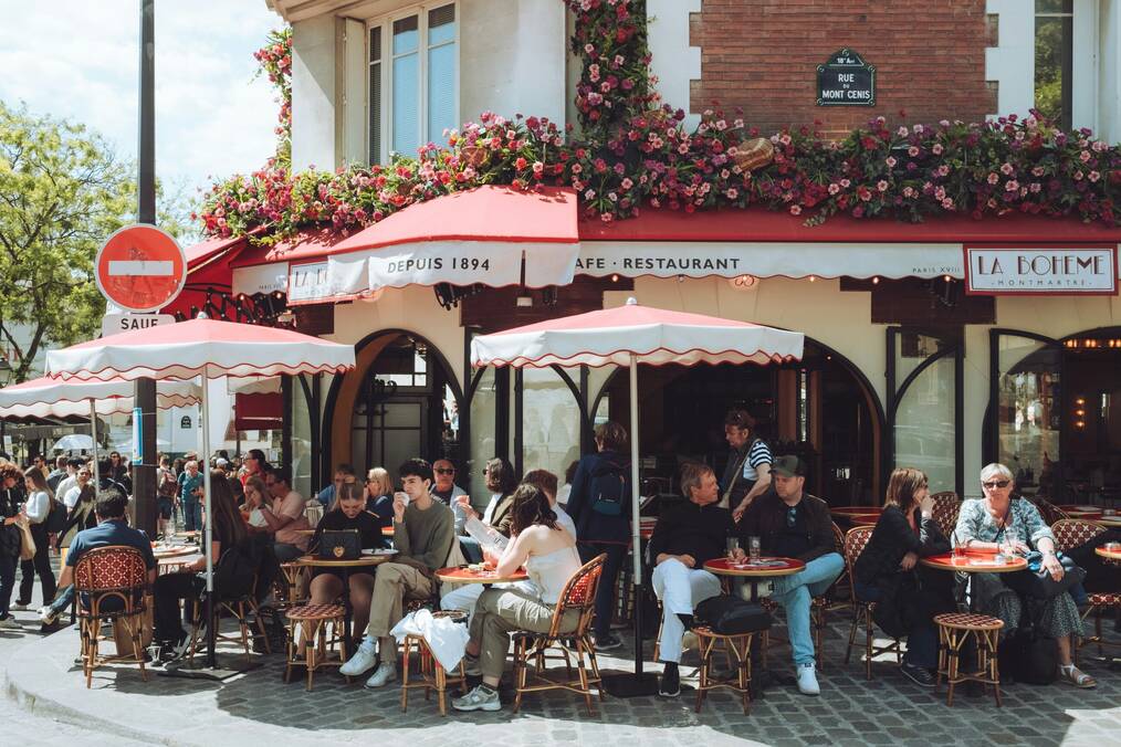 People sit on a terrace outside at a French cafe.